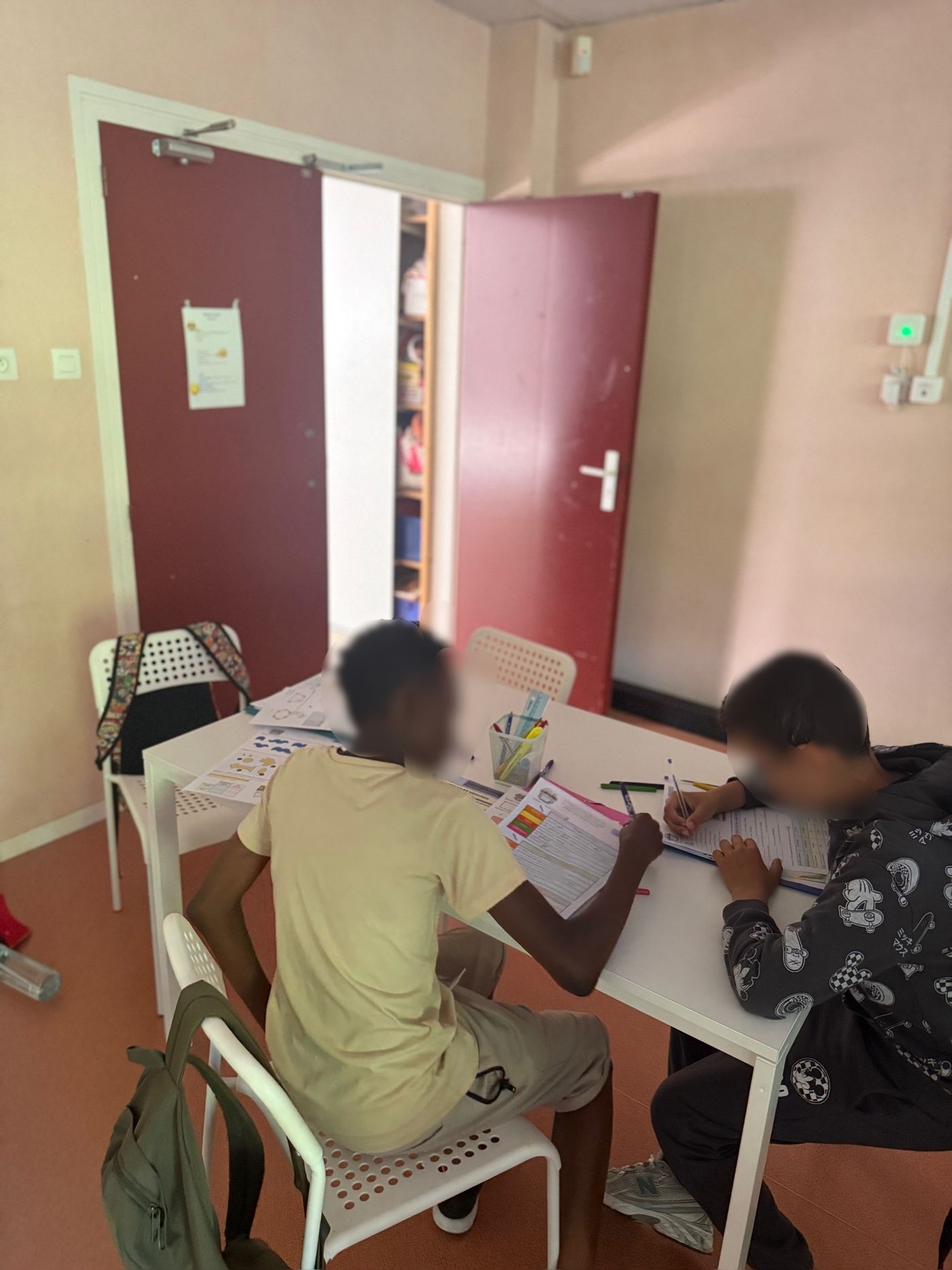 Deux élèves au travail côte à côte dans un autre coin de la bibliothèque, sur une petite table blanche.